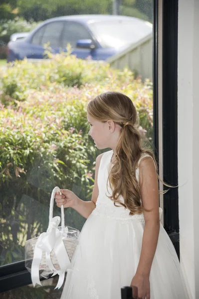 Flower girl with flower basket looking throw window — Stock Photo, Image