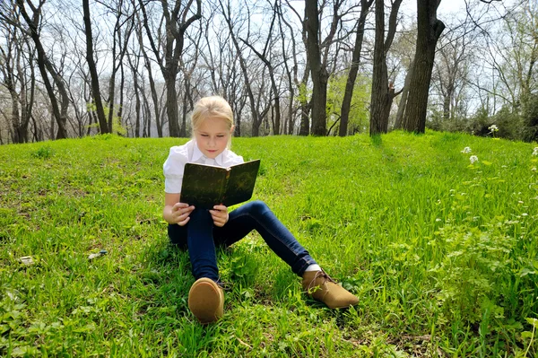 Petite fille assise et lisant un livre sur la nature — Photo