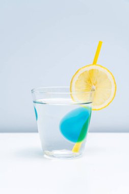 Bir bardak limonata ve beyaz masada taze bir limon.