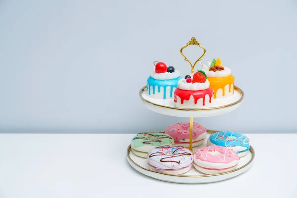 明るくカラフルなケーキやドーナツは2層のプレートに配置されています カラフルなフルーツケーキとティータイム — ストック写真