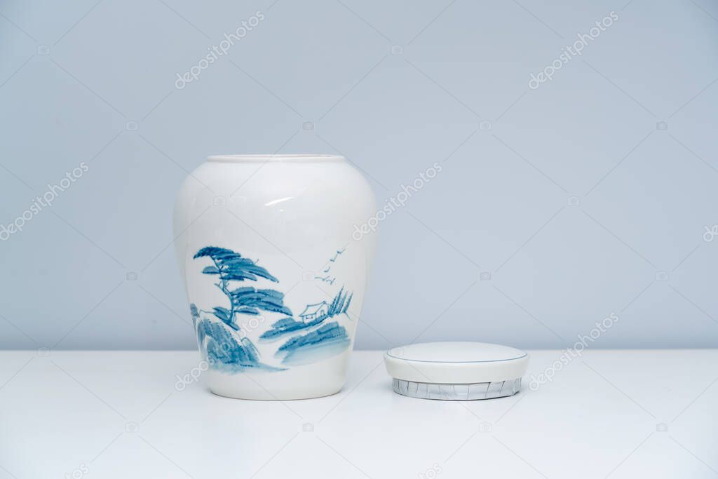 A white porcelain tea warehouse is placed on the white tabletop. A white porcelain jar on the table