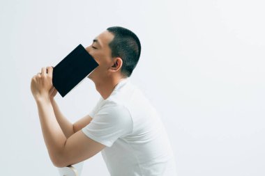 Yakışıklı bir Asyalı, beyaz arka planda oturmuş kitap okuyor..