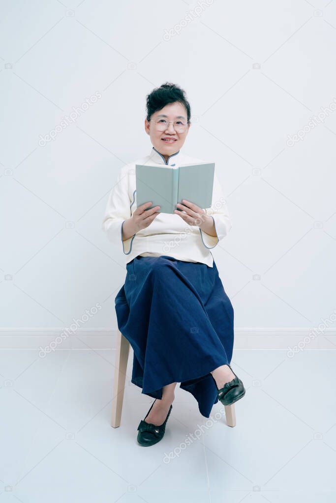 Middle-aged woman wearing traditional Chinese costume is reading