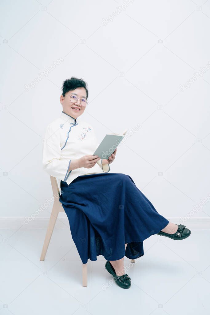 Middle-aged woman wearing traditional Chinese costume is reading