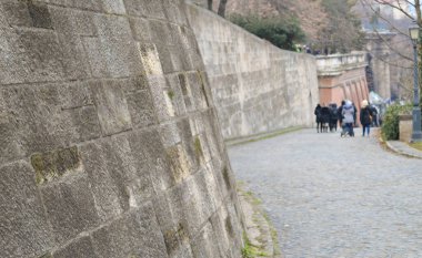 Budapeşte 'de arka planda tanınmayan insanların bulunduğu antik taş savunma duvarı.