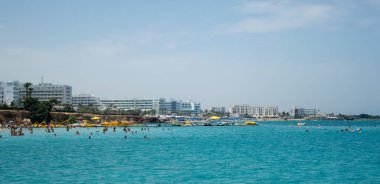 PROTARAS, CYPRUS - 16 Haziran 2018 'de Kıbrıs Rum Kesimi' nin Protaras kentinde güneşli bir günde yerel belediye plajı insanlarla dolup taşıyor. 