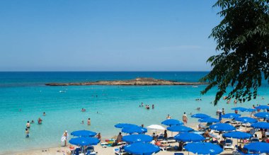PROTARAS, CYPRUS - 16 Haziran 2018 'de Kıbrıs Rum Kesimi' nin Protaras kentinde güneşli bir günde yerel belediye plajı insanlarla dolup taşıyor. 