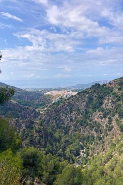 İspanya 'nın Frigiliana kentindeki eski bir sulama hendeği boyunca bir yürüyüş yolundan çevresindeki dağların ve resimli köyün manzarası..