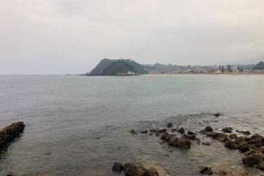 A beautiful seaside village with colorful houses, fishing boats, and green mountains in Ribadesella, Spain.
