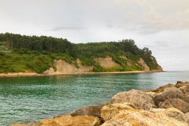 İspanya, Villaviciosa 'daki Rodiles Sahili, bulutlu hava altında yumuşak dalgalar, ıslak kum ve sakin, karamsar bir kıyı atmosferi var..
