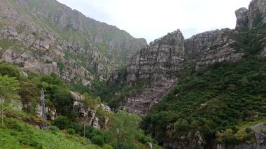 İspanya, Cantabria 'da dar bir dağ yolunda, sarp yeşil tepeler ve sakin bir su deposuyla çevrili bir baraj..