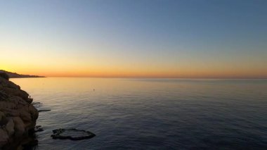 İspanya, Malaga 'da, Rincon de la Victoria' da gün doğumu, sahil boyunca sakin dalgalara yansıyan altın ışıkla.