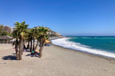 ALMUNECAR, SPAIN - 28 AĞUSTOS 2025: Fırtınalı Akdeniz Almunecar, Endülüs, İspanya 'daki güneşli plaja vuran derin mavi dalgalar.