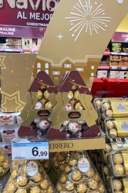 TORREMOLINOS, SPAIN - 21 Kasım 2025: İspanya 'nın Torremolinos kentindeki Carrefour' da düzenlenen Ferrero Rocher Noel şenlikli vitrininde altın madalyalar ve zarif mevsimlik markalar sergileniyor.