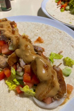 Tortilla 'ya sarılı ev yapımı shawarma taze sebzeler ve aromatik baharatlarla lezzetli bir yemek yaratır..