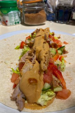 Tortilla 'ya sarılı ev yapımı shawarma taze sebzeler ve aromatik baharatlarla lezzetli bir yemek yaratır..