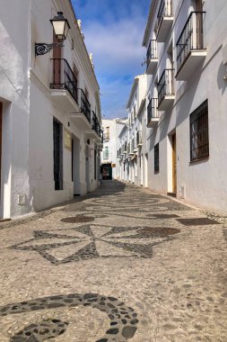 FRIGILIANA, SPAIN - 10 Mayıs 2025: Frigiliana, İspanya 'da beyazlatılmış evler ve renkli çiçeklerle çevrili büyüleyici dar sokaklarda huzurlu bir yürüyüş