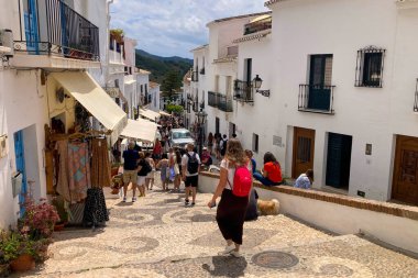 FRIGILIANA, SPAIN - 10 Mayıs 2025: Frigiliana, İspanya 'da beyazlatılmış evler ve renkli çiçeklerle çevrili büyüleyici dar sokaklarda huzurlu bir yürüyüş