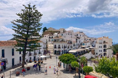 FRIGILIANA, SPAIN - 10 Mayıs 2025: Frigiliana, İspanya 'da beyazlatılmış evler ve renkli çiçeklerle çevrili büyüleyici dar sokaklarda huzurlu bir yürüyüş