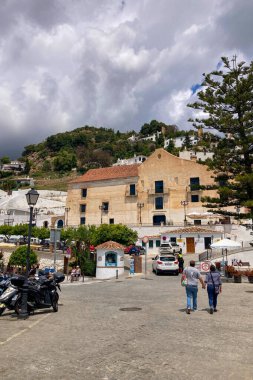 FRIGILIANA, SPAIN - 10 Mayıs 2025: Frigiliana, İspanya 'da beyazlatılmış evler ve renkli çiçeklerle çevrili büyüleyici dar sokaklarda huzurlu bir yürüyüş