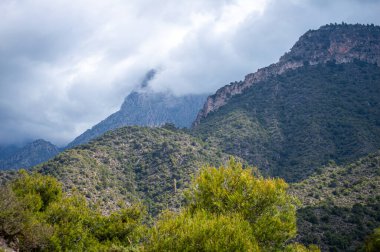 İspanya 'nın Frigiliana kentindeki eski bir sulama hendeği boyunca bir yürüyüş yolundan çevresindeki dağların ve resimli köyün manzarası..