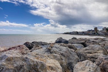 Yumuşak bulutlar sakin bir sahil üzerinde sürükleniyor, Akdeniz boyunca sakin bir kıyı havası yaratıyor..