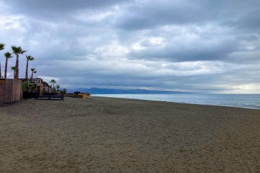 TORREMOLINOS, İspanya - 22 Kasım 2025: Yumuşak bulutlar denizde sürükleniyor, Torremolinos, İspanya 'da sıcak ve sakin bir kıyı sabahı atmosferi yaratıyor.