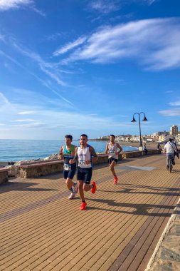 TORREMOLINOS, SPAIN - FEBRUARY 12026: Koşucular, İspanya 'nın Torremolinos kentinin güneşli zeminine karşı dayanıklılık ve enerji sergileyerek kıyı caddelerinde yarı maraton koşuyorlar.