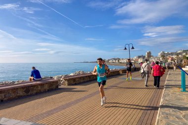 TORREMOLINOS, SPAIN - FEBRUARY 12026: Koşucular, İspanya 'nın Torremolinos kentinin güneşli zeminine karşı dayanıklılık ve enerji sergileyerek kıyı caddelerinde yarı maraton koşuyorlar.