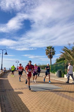 TORREMOLINOS, SPAIN - FEBRUARY 12026: Koşucular, İspanya 'nın Torremolinos kentinin güneşli zeminine karşı dayanıklılık ve enerji sergileyerek kıyı caddelerinde yarı maraton koşuyorlar.
