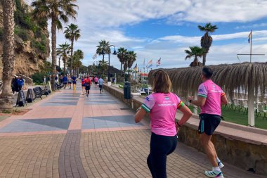 TORREMOLINOS, SPAIN - FEBRUARY 12026: Koşucular, İspanya 'nın Torremolinos kentinin güneşli zeminine karşı dayanıklılık ve enerji sergileyerek kıyı caddelerinde yarı maraton koşuyorlar.