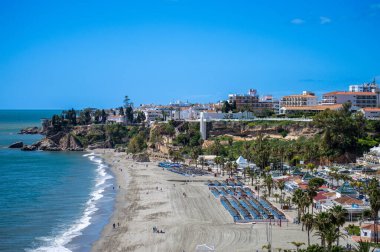 NERJA, İspanya - 22 Mart 2025: Işıldayan deniz ve büyüleyici şehrin muhteşem manzaraları, 22 Mart 2025 tarihinde İspanya 'nın Nerja kentinde nefes kesen kıyı manzaraları ve pitoresk bir atmosfer sunuyor.