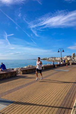 TORREMOLINOS, SPAIN - FEBRUARY 12026: Koşucular, İspanya 'nın Torremolinos kentinin güneşli zeminine karşı dayanıklılık ve enerji sergileyerek kıyı caddelerinde yarı maraton koşuyorlar.