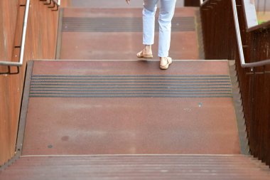 Yaz kıyafetleri içinde bir kadın paslı çelik bir merdivenden aşağı yürüyor, Avusturya, Avrupa