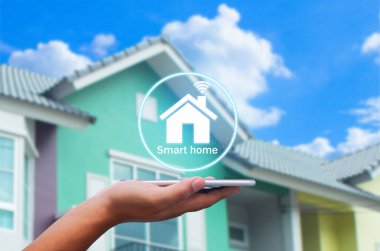 Bulanık evdeki akıllı ev uygulamalı akıllı telefonu arka plan olarak tutan eller.