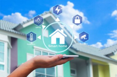 Bulanık evdeki akıllı ev uygulamalı akıllı telefonu arka plan olarak tutan eller.