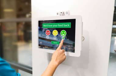 Müşteri memnuniyeti geribildirim anketi kavramı. Alışveriş merkezindeki gülümseme yüzünü seçen dijital tablet kullanan eller