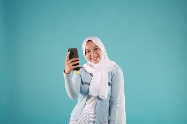 在蓝色背景下使用智能手机的亚洲女人的肖像 凉爽的冬季概念 — 图库照片