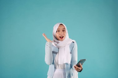 Mavi arka planda akıllı telefon kullanan Asyalı kadının portresi. serin kış konsepti.