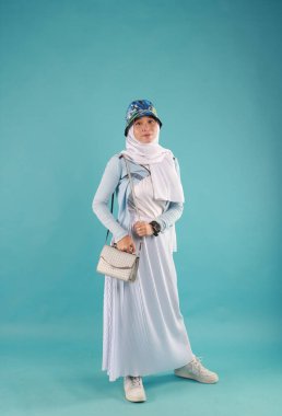 Güzel, zarif, Asyalı bir kadının mavi arka planda duran el çantasının moda fotoğrafı..