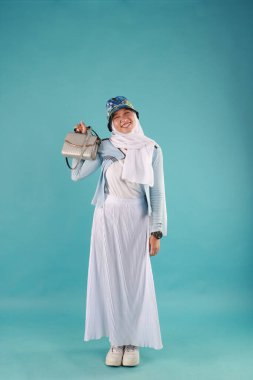 Güzel, zarif, Asyalı bir kadının mavi arka planda duran el çantasının moda fotoğrafı..