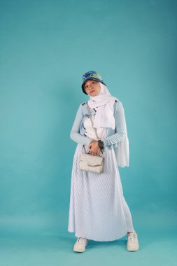 Güzel, zarif, Asyalı bir kadının mavi arka planda duran el çantasının moda fotoğrafı..