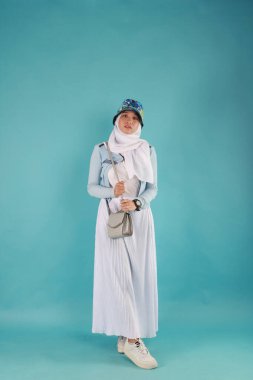 Güzel, zarif, Asyalı bir kadının mavi arka planda duran el çantasının moda fotoğrafı..