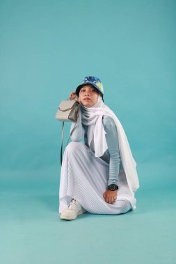 Güzel, zarif, Asyalı bir kadının mavi arka planda duran el çantasının moda fotoğrafı..