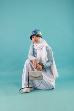 Güzel, zarif, Asyalı bir kadının mavi arka planda duran el çantasının moda fotoğrafı..