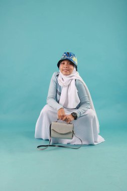 Güzel, zarif, Asyalı bir kadının mavi arka planda duran el çantasının moda fotoğrafı..