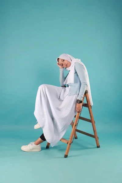 Mavi arka planda tesettürlü güzel Asyalı Müslüman kadının moda portresi.