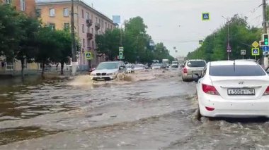 Tver, Rusya - 28 Haziran 2021: şehirde sel. Felaket! Yüksek su seviyesi. Yağmurlar, duşlar. Arabalar evlerin arasındaki cadde boyunca zar zor yüksek ve kirli sularda sürüyorlar. Uzun dalgalar ayrılır