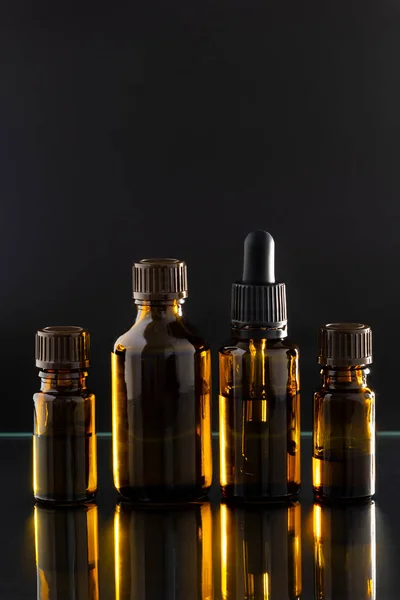 Aromatherapy essential oil dropper, bottles, black background, close up, vertical layout, copy space