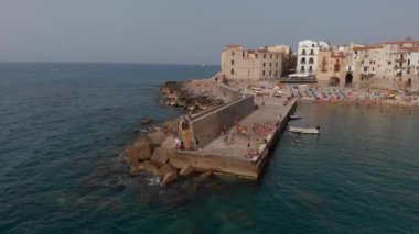 İnsanlar Cefalu 'daki iskeleden suya dalıyor.